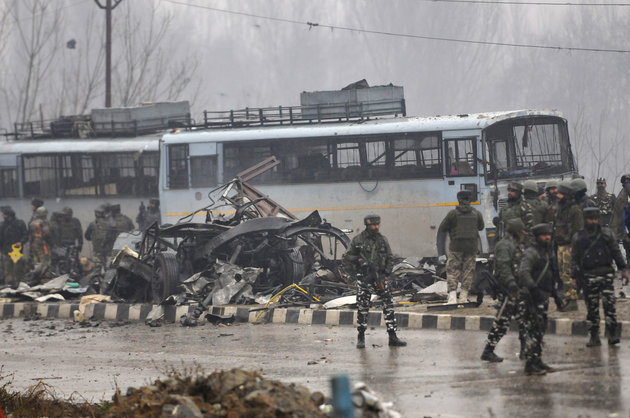 SRINAGAR, INDIA - FEBRUARY 14: Security forces near the damaged vehicles at Lethpora on the Jammu-Srinagar highway, on February 14, 2019 in Srinagar, India. At least 30 CRPF jawans were killed and many others injured in an improvised explosive device (IED) blast at Lethpora. Police sources say that the attack was likely carried out by a suicide bomber, who rammed an explosive-laden car into the CRPF bus. The bus was part of an army convoy coming from Jammu to Srinagar. (Photo by Waseem Andrabi/Hindustan Times via Getty Images)